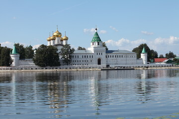 ancient white-stone monastery with fortress walls, towers and golden domes on the river bank © mrivserg