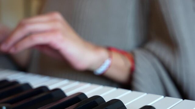 Female hands playing a beautiful melody on the piano in a cozy home setting, showcasing musical talent