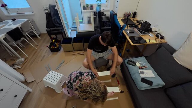 Couple assembling furniture on living room floor with tools and parts in home interior, timelapse