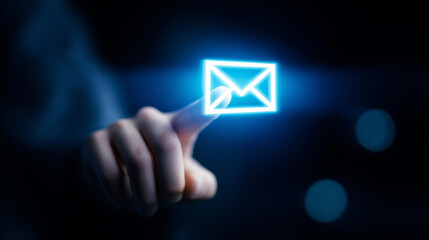 Fototapeta premium Hand touching glowing digital email icon, symbolizing online communication, contact, and network connection