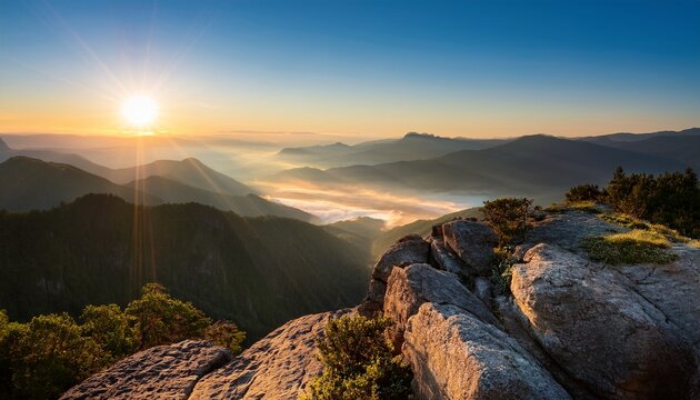 rocky ledge overlooks misty mountain valley at sunrise gentle sun rays illuminate vast mountain range with layers of peaks nature outdoor calm landscape