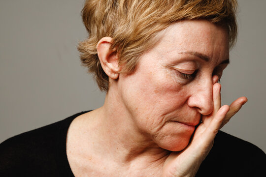 Portrait of mature woman with hand on face showing realistic skin and aging signs.