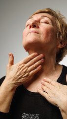 Naklejka premium Mature woman touching neck in authentic skincare and healthy aging concept with realistic skin texture.