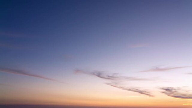 A serene, abstract twilight sky video with a smooth gradient from deep navy blue to pastel orange, subtle push-in, ethereal clouds. Concept of corporate optimism and innovation