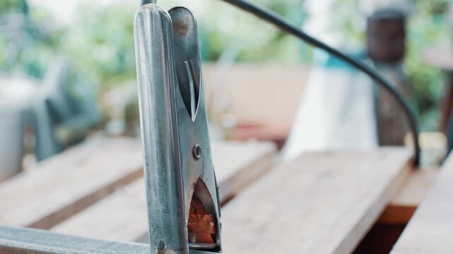 Close up of welder attaching welding machine ground clamp to metal construction before welding steel frame in workshop environment