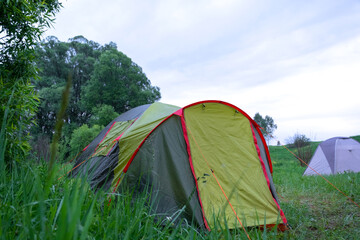 Close up of tent entrance in forest, campsite surrounded by grass and trees, travel, outdoor tourism and exploration, camping adventure background. © Ольга Симонова