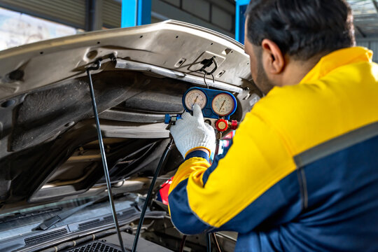 Car mechanic man working on air pressure gauge measuring air condition system in auto repair service shop