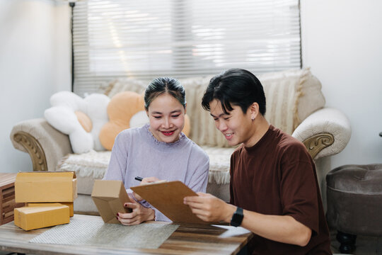 Asian Couple Checking Orders with Clipboard and Parcels, Small Business Owner Concept