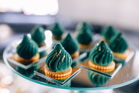 Elegant green petit fours on mirrored tray for birthday party dessert and celebration catering display