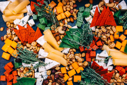 Colorful charcuterie and cheese board with nuts, herbs and bite-sized appetizers for happy gatherings
