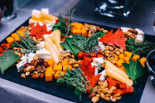 Colorful cheese platter and charcuterie board with nuts and herbs for parties and entertaining