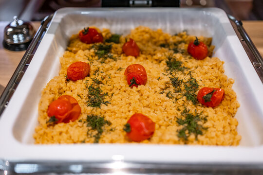 Warm couscous with roasted cherry tomatoes and herbs served buffet-style in a catering tray