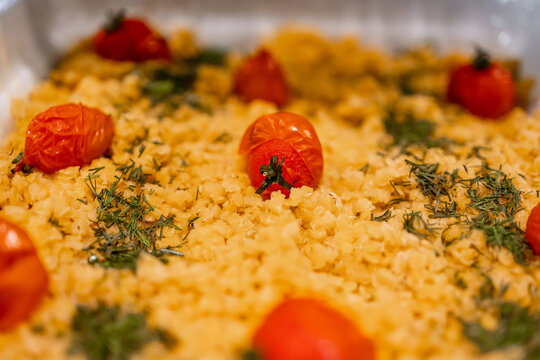 Roasted cherry tomatoes on herbed couscous bake with fresh dill and golden grains