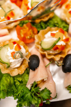 Assorted appetizers and canap&eacute;s with rolled ham, tartlets and olives on a buffet platter