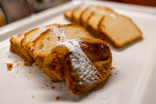 Sliced pound cake with powdered sugar on a white plate, homemade dessert for tea or breakfast