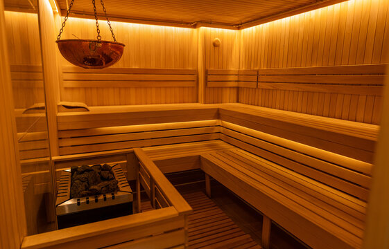 Warm wooden sauna interior with benches, hot stone heater and ambient lighting for relaxation