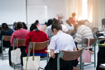 Obraz premium Focused students sitting in classroom taking academic examination or final test, back view, authentic school atmosphere, bright cinematic lighting, education and evaluation concept.