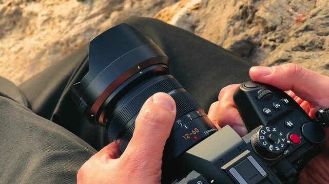 Close-up of photographer hands adjusting camera lens to capture travel moments, tourism and videography concept. High quality 4k footage