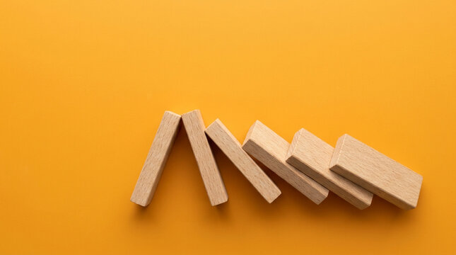 Seven wooden dominoes falling cascade aerial view on vivid amber, cascading risks compounding risk chain reaction WEF global risk concept.