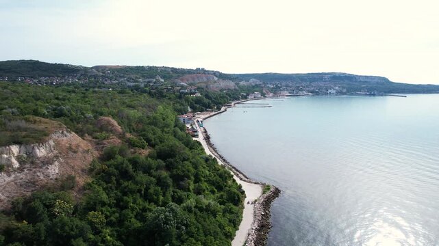 Aerial view of the scenic coastline with lush green cliffs and a promenade along the calm Black Sea in Balchik, Dobrich Province, Bulgaria.