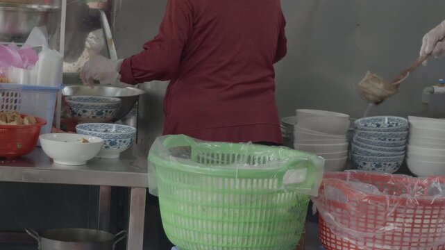 Two Vietnamese women preparing authentic Bun Rieu, scooping snails and broth, boiling noodles at a street food stall in Saigon
