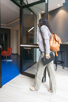 Businesswoman walking through office entrance carrying tablet