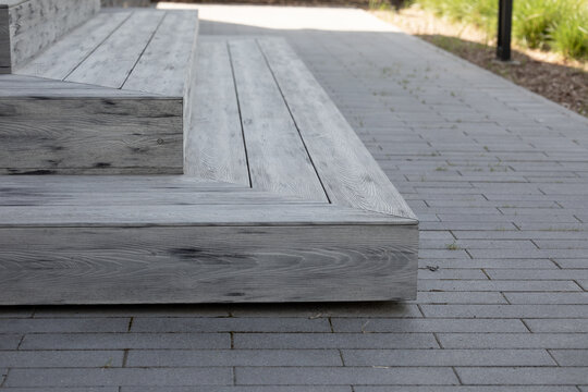 Gray composite deck steps with artificial wood planks, WPC material on paved pathway, modern outdoor hardscape design, weather resistant surface