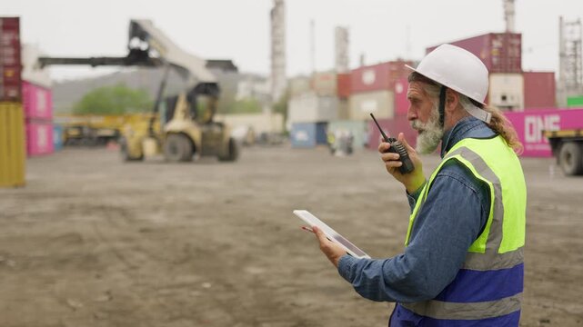 A senior logistics manager meticulously inspects freight data on a tablet, coordinating container shipments at a busy industrial port for supply chain optimization.