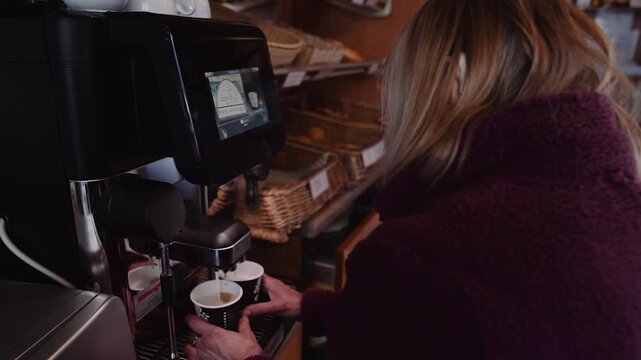 &Auml;ltere Verk&auml;uferin bereitet frischen Cappuccino in einer B&auml;ckerei zu