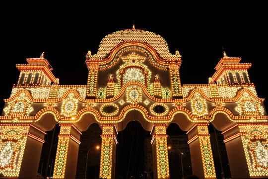 The entrance arch (Portada) to the Seville April Fair at night, illuminated by thousands of light bulbs. Seville Fair 2026, Andalusia, Spain. Fair lighting.