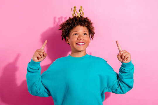 Joyful child wearing a gold crown smiling confidently against a pink background celebrating imagination and playful self-esteem