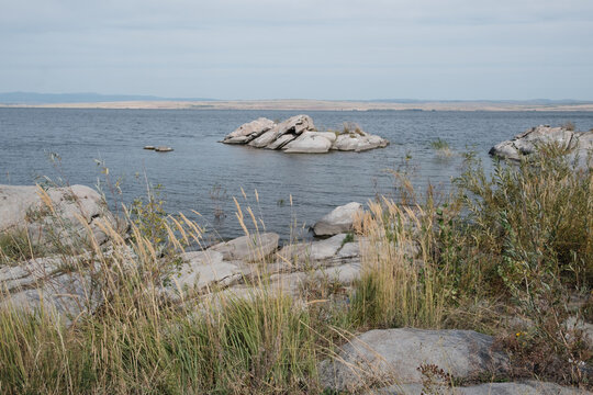 Scenic landscape of Bukhtarma reservoir in East Kazakhstan with granite rocks and wild grass. Universal outdoor background for travel industry, environmental projects or leisure concepts.
