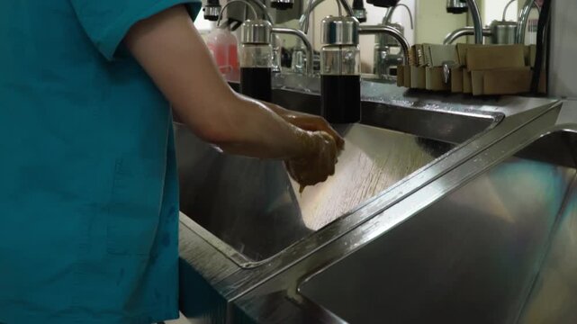 Surgeon washing hands thoroughly at sink before sterile procedure in modern operating theater