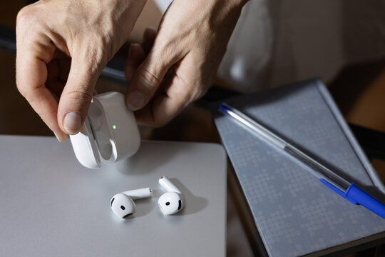 Person holding airpods charging case with earbuds