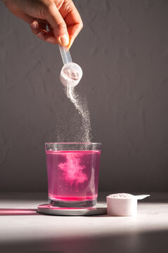Pouring food supplement powder in glass of water. Collagen, protein powder, vitamins.