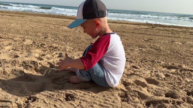Little child stepping on a sandy beach living footprints and later sitting on the sand. 4K.