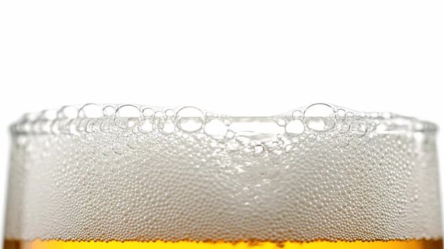 Close-up of beer in a glass, with bubbles, foam, and froth against a white background