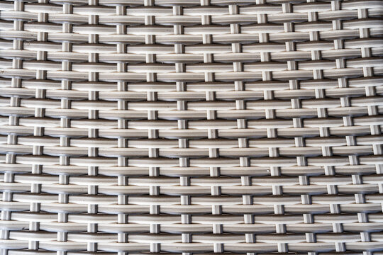 Detailed close-up texture of woven synthetic rattan, showcasing the intricate patterns and design of modern furniture material, ideal for interior design concepts and home decor presentations
