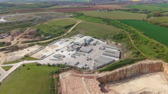 Aerial view of Marshalls industrial site with stacks of concrete blocks and a quarry pit surrounded by green fields in Maltby, England, United Kingdom.