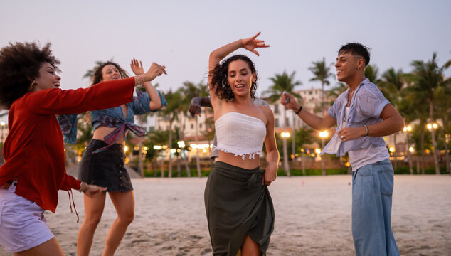 A diverse group of multicultural friends enjoying summer moments on the beach, dancing, laughing