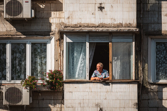 Senior man coping with urban heatwave in apartment window