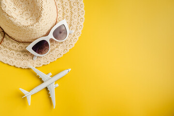Travel-themed flat lay, summer holiday background. Toy model airplane, sunglasses, sun hat over...