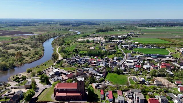 Aerial drone view of the historic town Pyzdry in Greater Poland, parish church of the Nativity of the Blessed Virgin Mary, Warta river winding through the valley, riverside boulevards, rural landscape