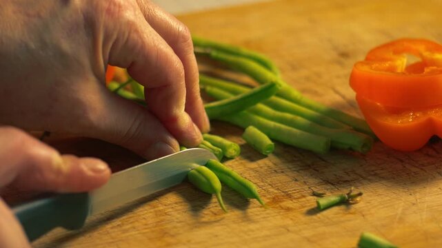 Hands chopping raw green beans