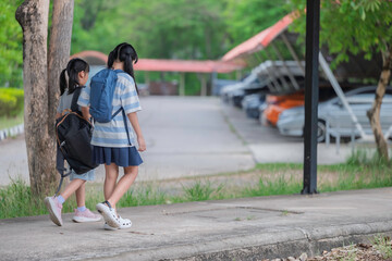 Obraz premium Happy Asian student girls with backpacks walking and running together at school. Back to school concept with kids smiling and having fun outdoors while going to classroom for education and learning.
