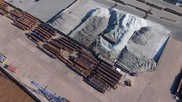 Aerial view of PD Ports showing large piles of aggregate and stacks of industrial steel beams in an open storage yard in Scunthorpe, England, United Kingdom.