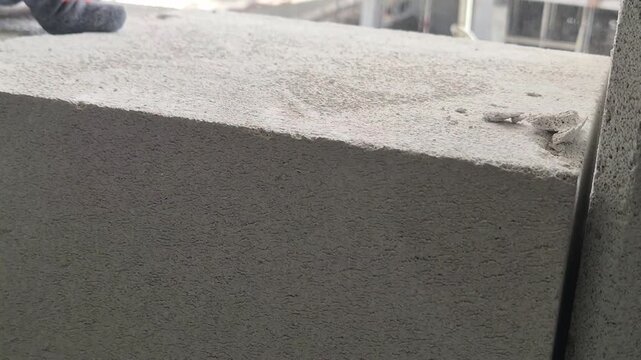 Slow motion close up of a construction worker using a rubber mallet to tap an autoclaved aerated concrete block into perfect position.
