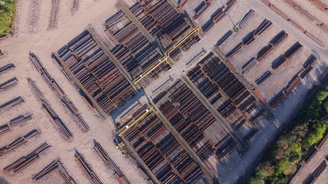 Aerial view of PD Ports industrial yard featuring organized stacks of steel beams and yellow gantry cranes under bright daylight in Scunthorpe, England, United Kingdom.