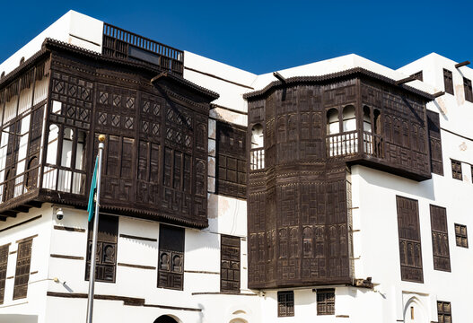 Exterior view of a traditional white building with dark wood rawashin windows in the Yanbu Historic Area of Saudi Arabia