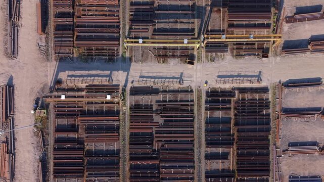 Aerial view of PD Ports industrial yard featuring organized stacks of steel beams and yellow gantry cranes under bright sunlight in Scunthorpe, England, United Kingdom.
